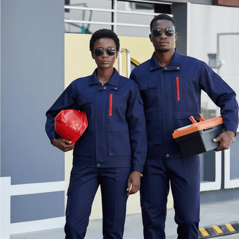 5. Safetywear & PPE - Industrial Suits in Kenya Two individuals in blue work uniforms and sunglasses stand confidently. One holds a red helmet, the other a toolbox, in an industrial setting.